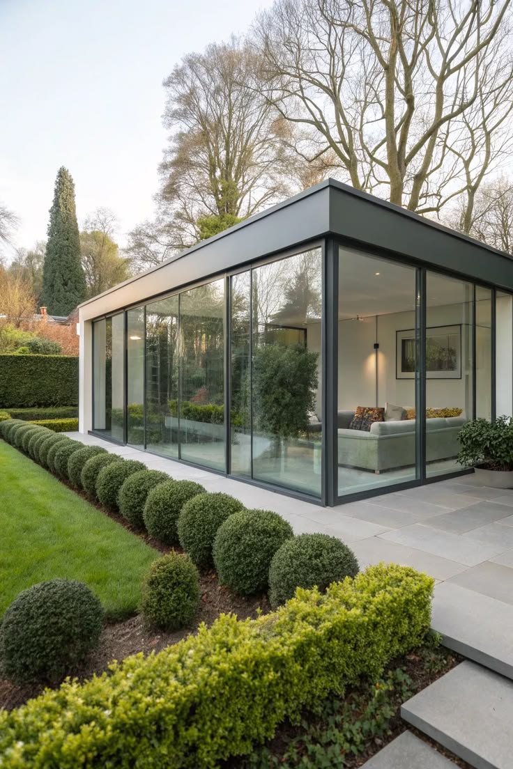 Extension vitrée en aluminium avec toiture plate donnant sur un jardin